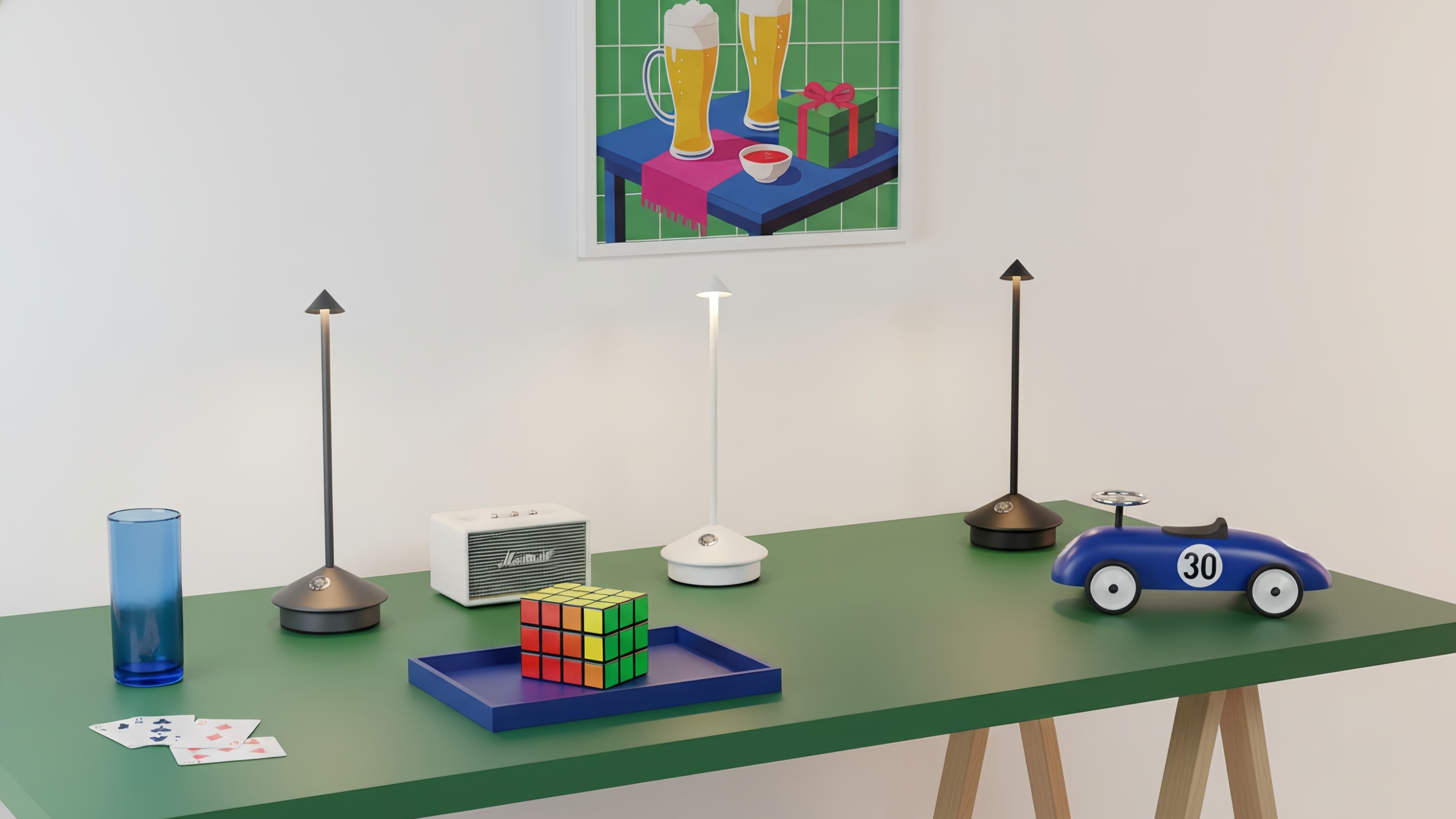 Pina Tischleuchte auf einem grünen Tisch mit verschiedenen Farben